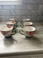 Six matching floral mugs on countertop