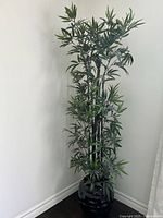 Full view of tall artificial plant in corner showing size and planter