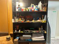 Full shelving unit with paint, cleaners, tools, level, paper rolls and drop cloths