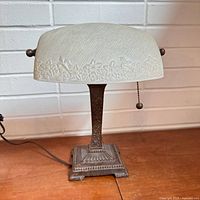 Front view of banker’s lamp showing frosted floral glass shade, decorative metal column and base