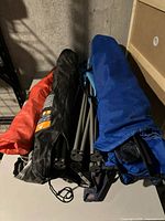 Six camping chairs in various colored carrying bags laid side-by-side on a table.