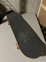 Top view of skateboard with black grip tape, showing slight wear.