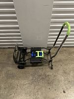 Side view of the hand truck showing black metal frame, green padded handles, and wheels.