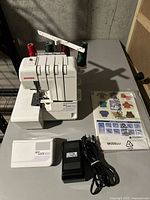 Front view of Janome MyLock 504D overlock machine with colored thread spools and accessories in front