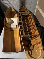 Top-down view of the model boat hull showing internal frame and separate hull mold alongside the stack of blueprints