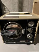 Front and top view of Ritter M7 SpeedClave autoclave sterilizer showing control panel, pressure gauge, temperature and pressure knobs, and chamber door with caution-hot sign.