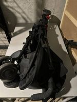 Photo showing the folded Maclaren stroller with wheels and frame detail on a white table.