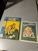 Top view of table with two vintage Walt Disney paint books, Pluto and Snow White