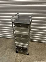 Front view of the chrome metal storage shelf with 10 drawers and caster wheels.