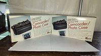Two sealed retail boxes of Zbag VC15 camcorder/photo cases on table
