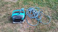 Top view of robotic pool cleaner and coiled cable on grass