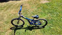 Left side view of entire blue Schwinn Falcon kids bike on grass