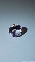 Close-up photo of 2.27ct natural pink purple amethyst gemstone, showing oval faceted cut and color variation.