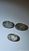 Three oval cabochon cut natural black rutilated quartz gemstones displayed on white background, showing black needle-like inclusions inside clear quartz.