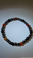 Full view of the natural gemstone stretchy bracelet showing arrangement of black onyx, shiny hematite, and red agate beads.