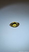 Pear shaped golden citrine gemstone on white background showing full stone and facets.