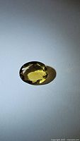 Oval cut natural golden citrine gemstone shown on white background with clear facets and high luster.