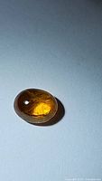 Oval cabochon cut golden yellow sapphire stone under lighting showing its internal characteristics and polished surface.