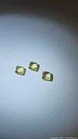 Three square fancy cut lemon citrine gemstones on white background, showing transparency and light lemon yellow color.