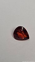 Front view of the pear cut deep orange Spessartite garnet on a white background, showing gemstone clarity and color.