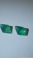 Pair of vivid green onyx gemstones, fancy cut, shaped like elongated diamonds, showing translucent green color with smooth polished surface.
