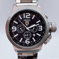 Front view of Ferrari chronograph watch showing black dial, sub-dials, logo, crown and bracelet