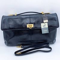 Front view of black lizard leather handbag with hang tag attached and shoulder strap displayed
