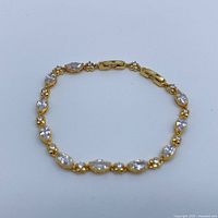 Full view of gold-tone crystal tennis bracelet laid flat in oval shape