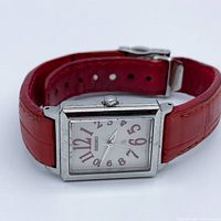 Watch angled view showing dial, case and red leather strap