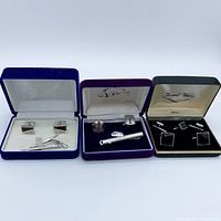 Three boxed cufflink and tie clip sets