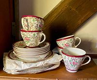Stack of saucers, cups and square plates showing pattern and quantity