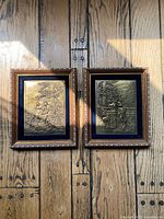 Both framed bronze bas relief plaques side by side on wall