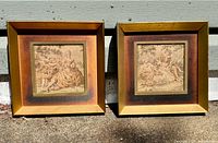 Both framed needlepoint pieces side by side outdoors