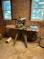 Full view of radial arm saw on stand with blades laid out on table