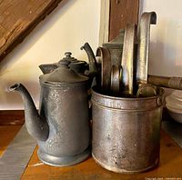 Two metal teapots and nested measuring cups in holder on shelf