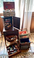 Overall lot showing sewing table, spool cabinet, floral sewing chest, two fabric baskets and contents