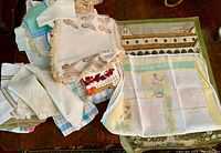 Pile of assorted linens showing printed building tea towel, fringe napkins, plaid towels and Guatemala tea towel
