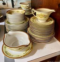 Stacks of bowls, plates and gravy boat showing pattern and gold rims