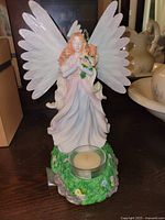 Standing angel figurine holding bouquet with tealight holder