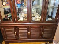 Front view of the lower section showing dark brown wood louvered doors with brass handles and solid cabinet base.