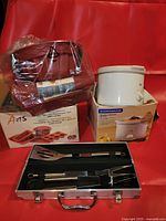 All three items: boxed bakeware set, slow cooker box, BBQ tool case