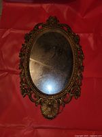 ornate oval mirror with brass-tone decorative frame