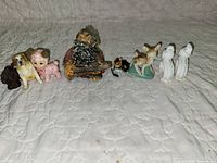 First group of seven assorted figurines including dog, baby, woodsman, small dog, fawn and pair of white birds