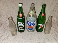Front view of five vintage glass soda bottles showing brands and sizes