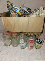 Seven branded glasses in front of shipping box