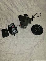 Vintage camera with charger, battery pack, and Sony CD walkman on a white quilted surface