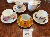 Top view of the five fine china teacups and saucers plus teapot, showing floral patterns and gold accents