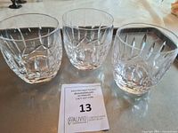 Three Waterford Crystal tumblers arranged on a metal tray, showing the cut crystal pattern and clarity of the glasses.