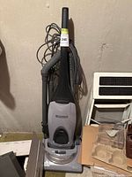 Full view of upright Kenmore vacuum cleaner showing hose, power cord, clear dust compartment and base