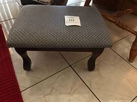 Footstool angled side view showing mahogany wooden legs and fabric upholstery